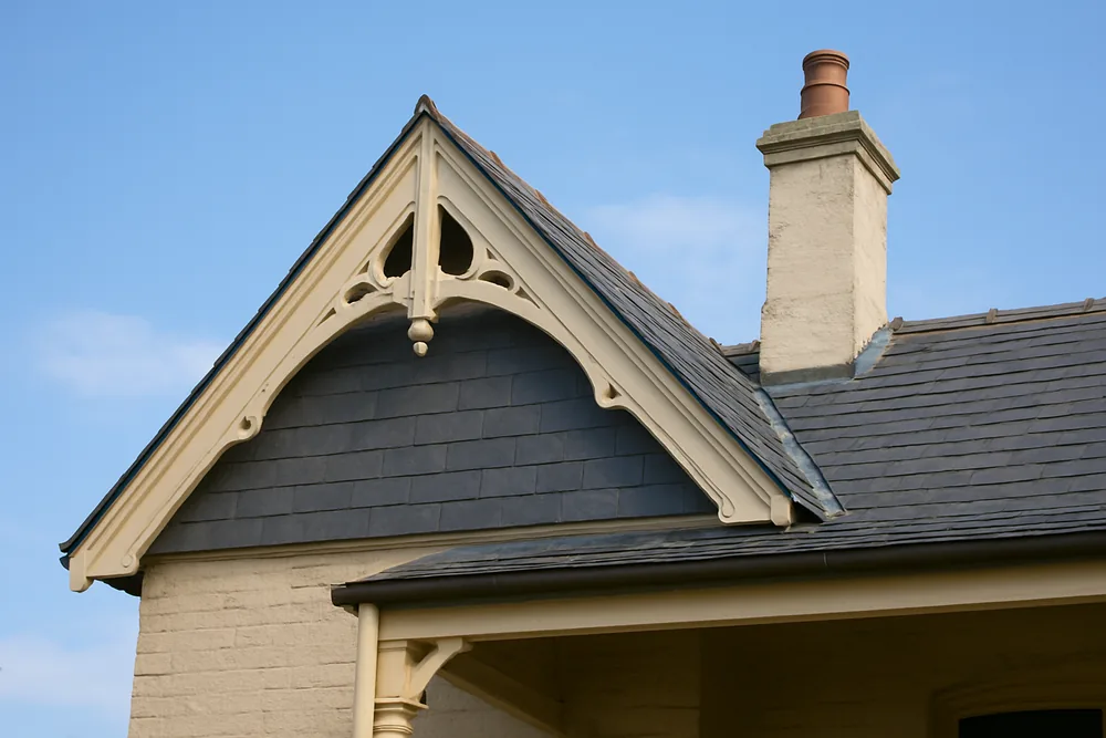 A slate gable with a decorative timber bargeboard and a rendered chimney with a terracotta pot — heritage slate roofs, Sydney. Illustrative example.